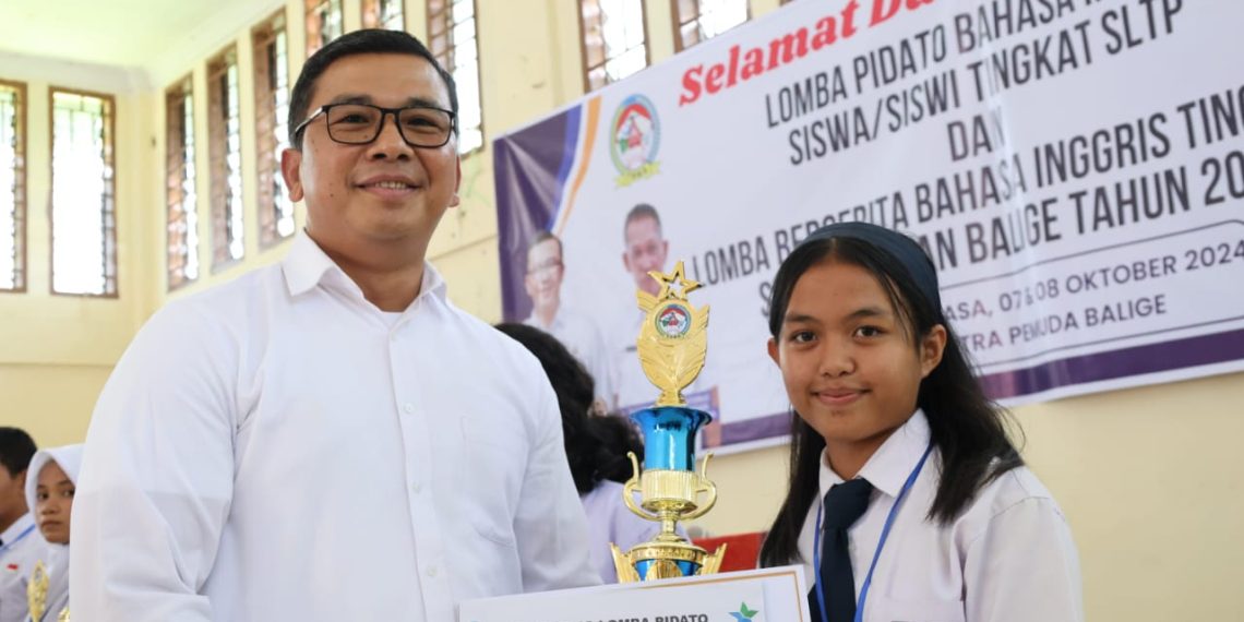 Pjs Bupati Toba, Dr Agustinus Panjaitan menyerahkan piala kepada Regina, Siswi SMP Budi Dharma Balige, juara 1 Lomba Pidato Berbahasa Inggris Tingkat SMP, se-Kecamatan Balige, Kabupaten Toba.