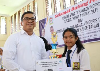 Pjs Bupati Toba, Dr Agustinus Panjaitan menyerahkan piala kepada Regina, Siswi SMP Budi Dharma Balige, juara 1 Lomba Pidato Berbahasa Inggris Tingkat SMP, se-Kecamatan Balige, Kabupaten Toba.